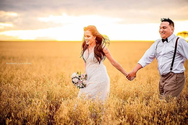 Casal de mãos dadas caminhando em um campo dourado